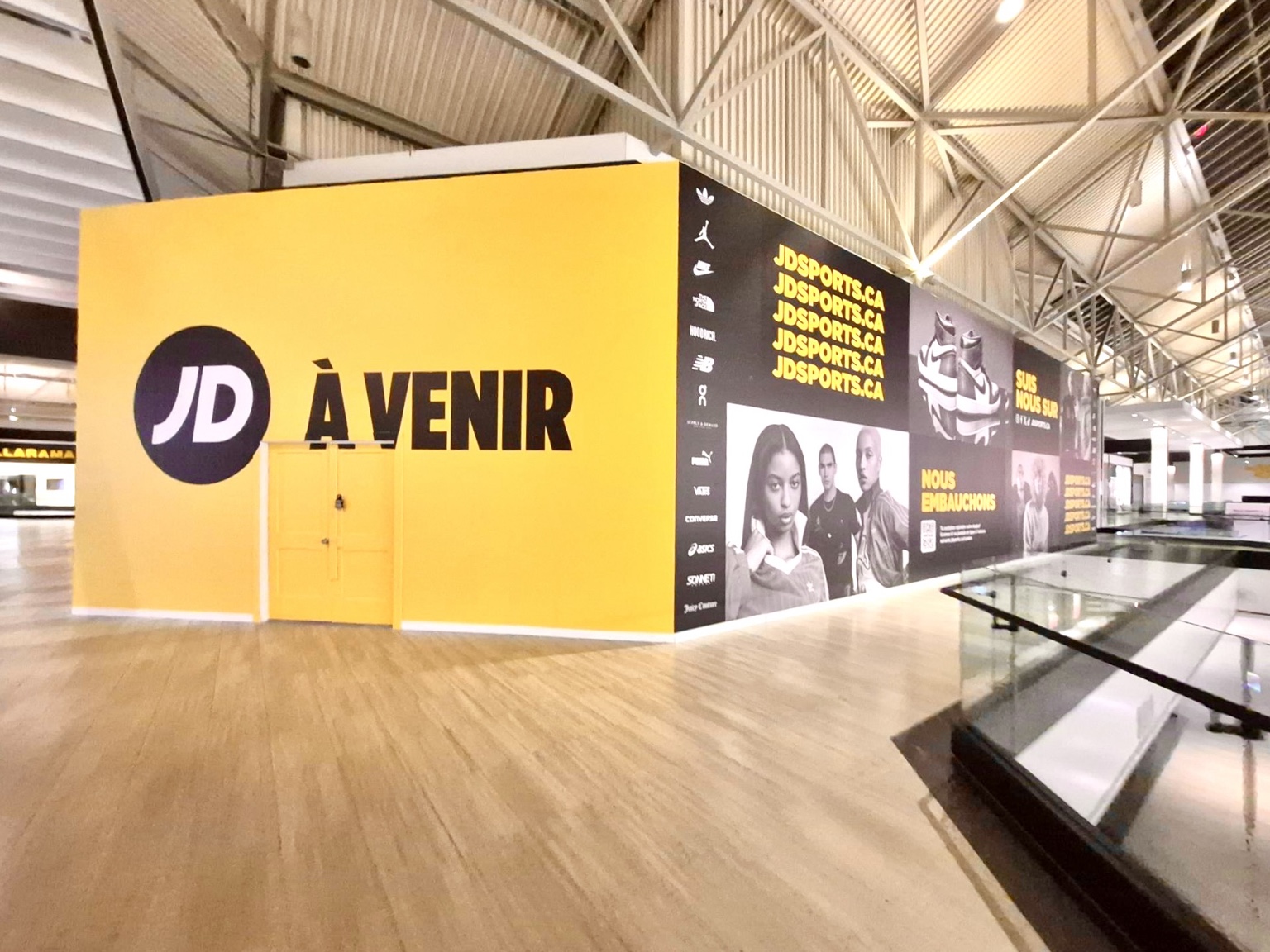 Yellow coming-soon graphics covering a mall corner-unit barricade