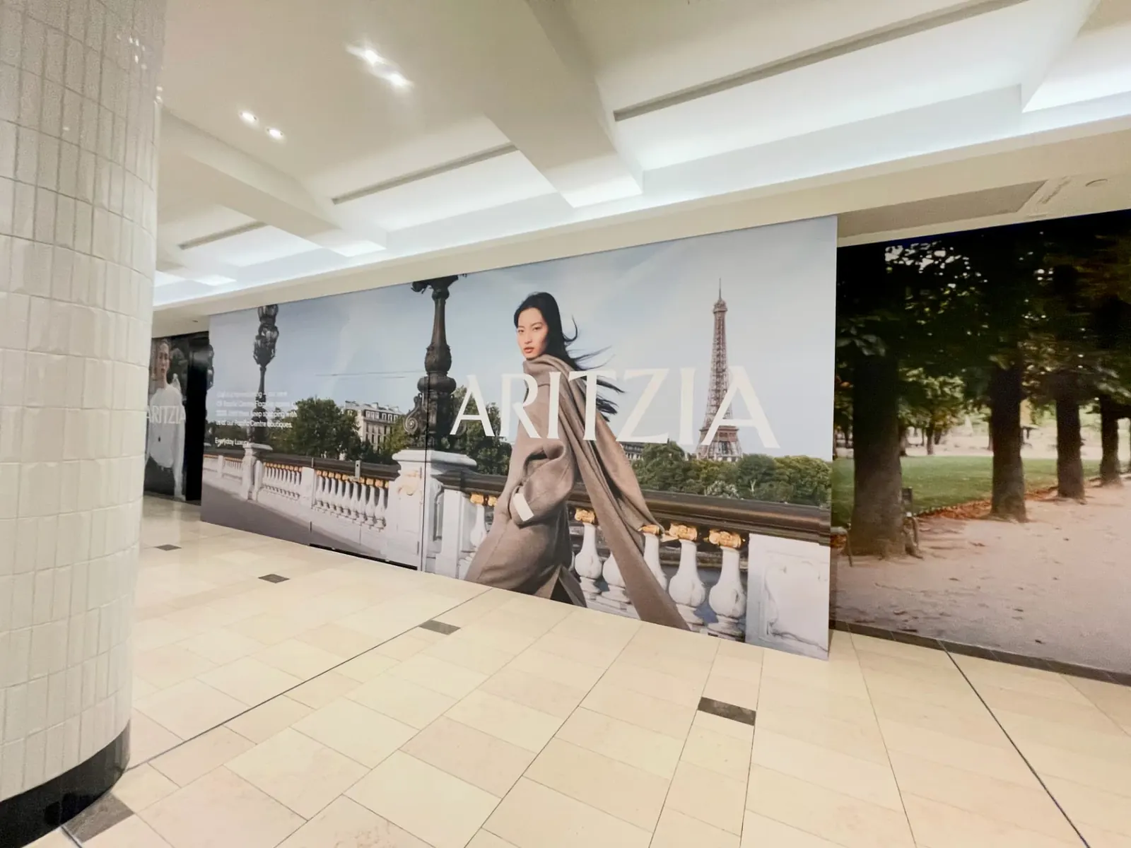 Full-bleed Aritzia campaign panel on the CF Pacific Centre hoarding